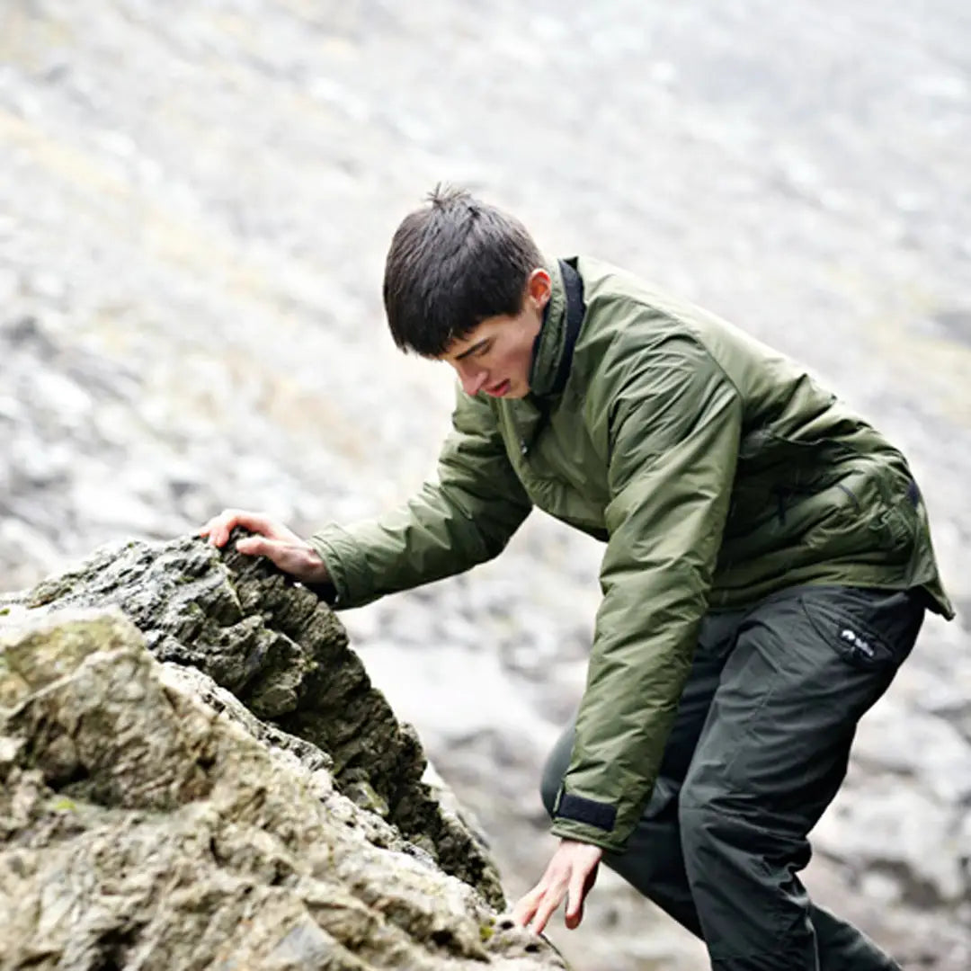 Person in a green jacket climbing rocky terrain in a Buffalo Mountain Shirt