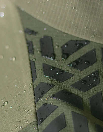 Bushbuck Alpine Waterproof Jacket in water-resistant olive green fabric with black geometric pattern for wet weather country clothing