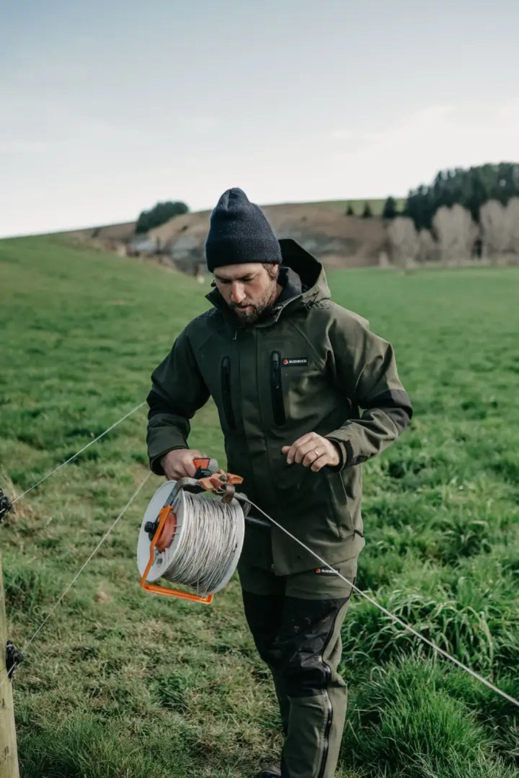 Man in outdoor gear with wire spool wearing Bushbuck Defender Waterproof Jacket for hunting and country clothing