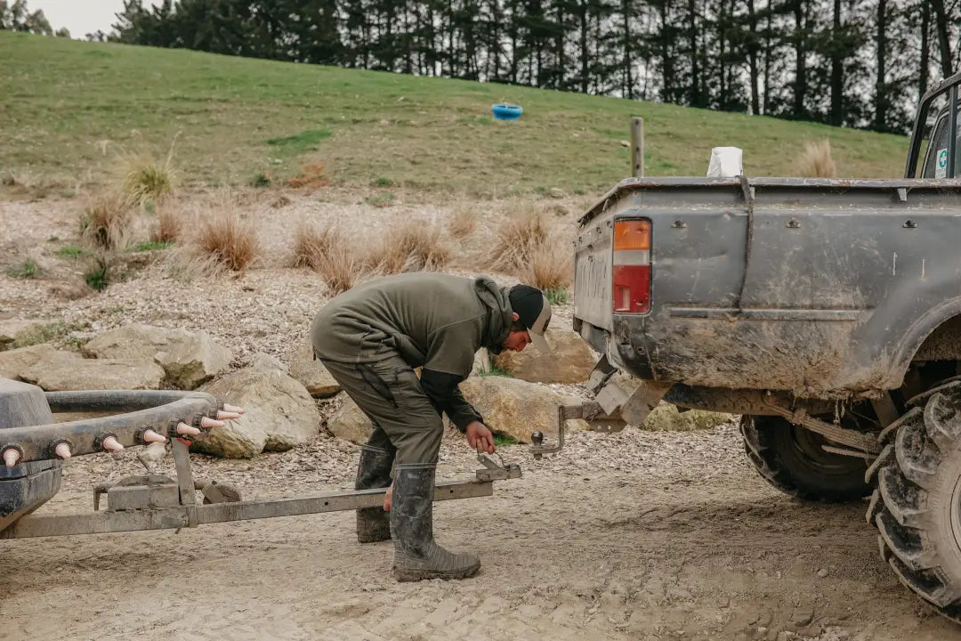 Muddy pickup truck with trailer hitch wearing Bushbuck Frontier Windproof Fleece Pullover with chest pocket in country clothing style