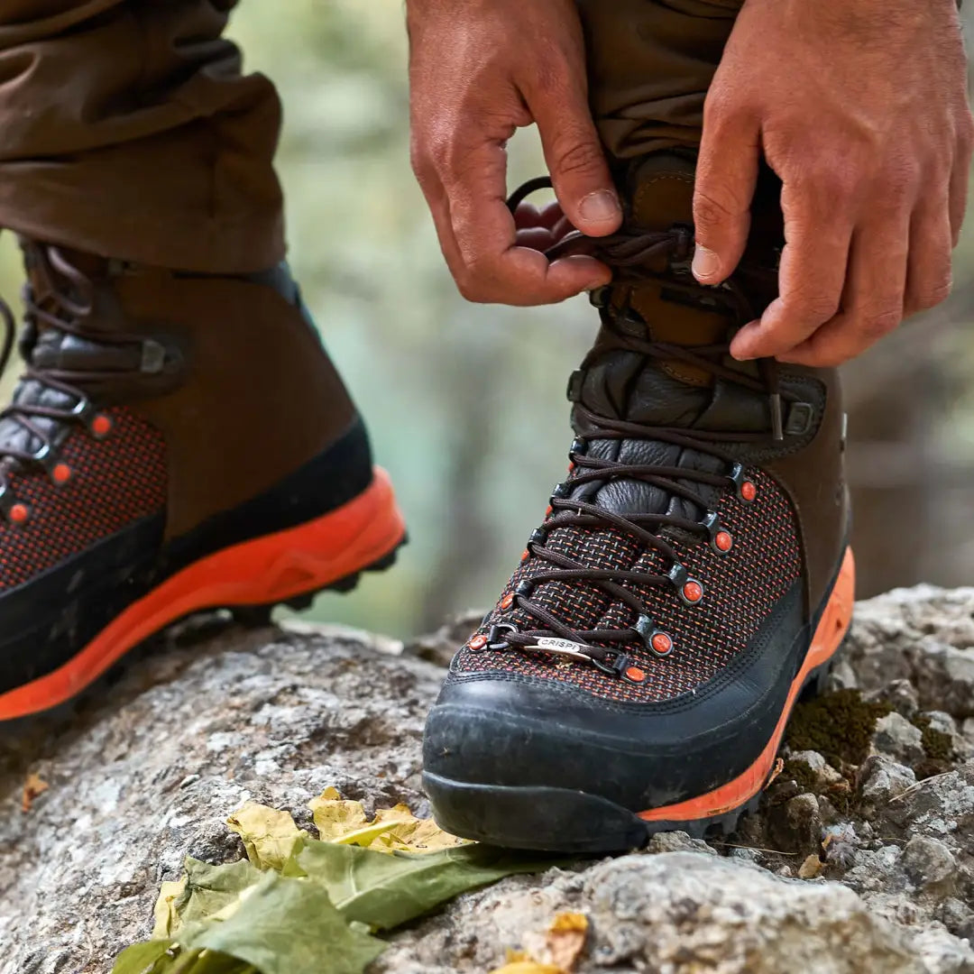 Hiking boot with orange accents laced up on rocky surface for outdoor adventures