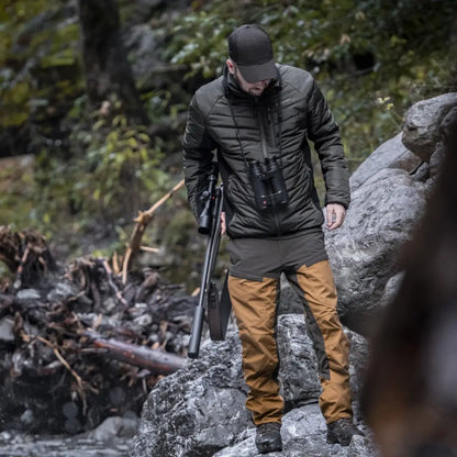 Person in Deerhunter Moor Softshell jacket on rocky terrain with camera tripod