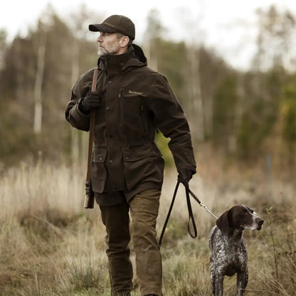 Hunter and dog in a field showcasing Deerhunter Pro Gamekeeper Jacket for ultimate outdoors