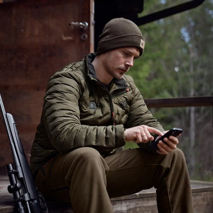 Man in military-style clothing using smartphone while wearing Clim8 Insulated Jacket