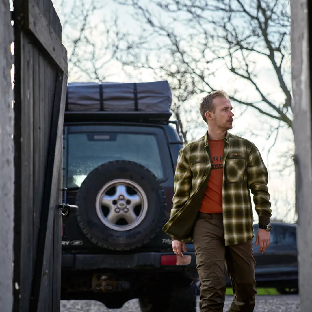 Man in a plaid Folke Shirt Jacket standing by a vehicle with roof rack