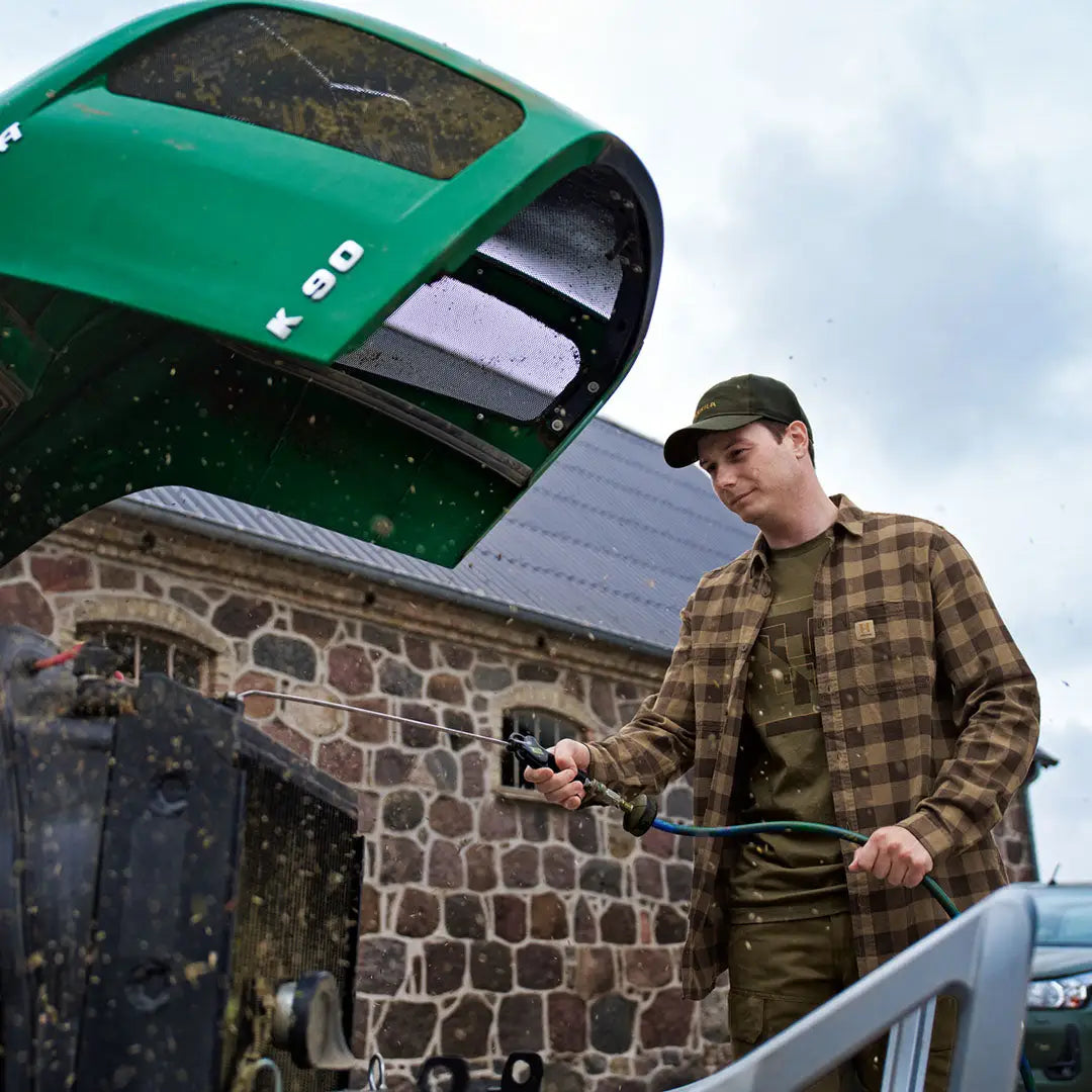 Man washing a green tractor while wearing Harkila H-logo Short Sleeve T-Shirt for outdoors