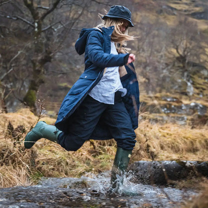 Woman in outdoor gear joyfully jumping in puddle wearing Hoggs of Fife ladies long coat