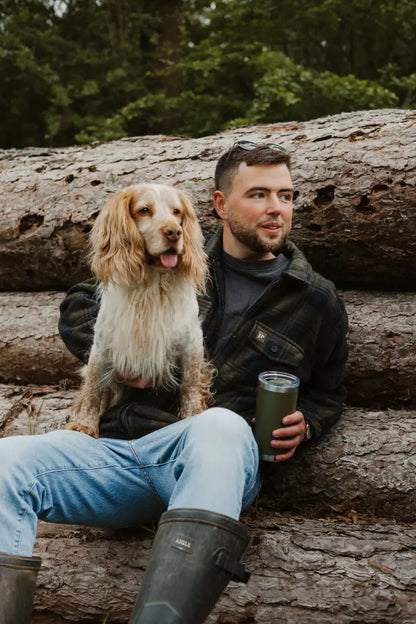 Man with dog sitting on logs wearing Jack Pyke Tundra Shirt for outdoor adventures
