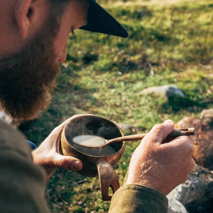 Wooden bowl of steaming soup in a Kupilka Classic Cup, perfect for outdoors lovers