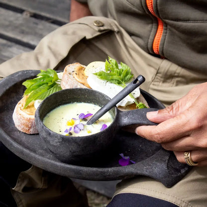 Rustic black Kupilka Plate with soup and sandwiches on a cozy country table
