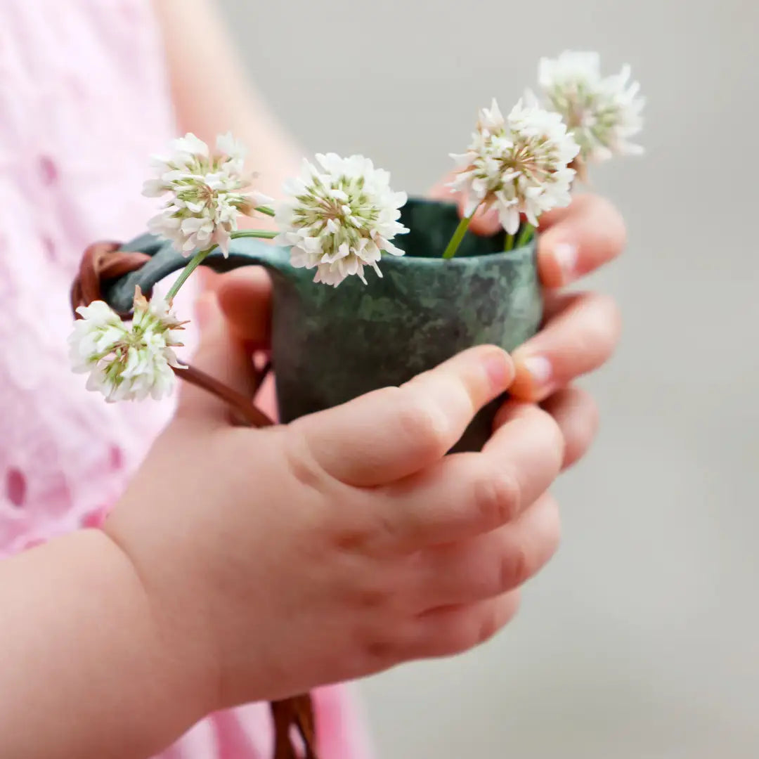 Handmade ceramic vase with clover flowers in a Kupilka Shot Cup, perfect for country clothing