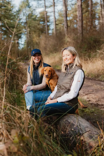 Two women and a dog sitting on a log in stylish New Forest Ladies Heated Gilet