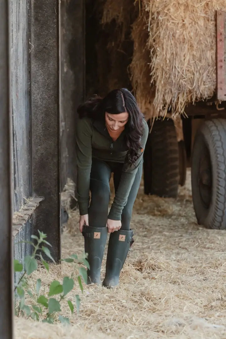 Woman adjusting green rubber boots in New Forest Ladies Trail Fleece for forest trail walks