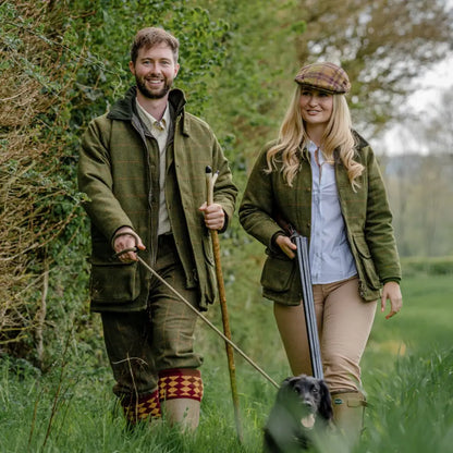 Couple in country attire walking a dog, showcasing stylish New Forest Tweed Breeks