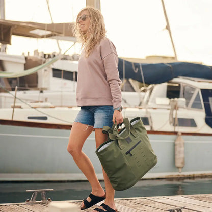 Woman with a green waterproof tote bag featuring sleek welded seams on a boat dock