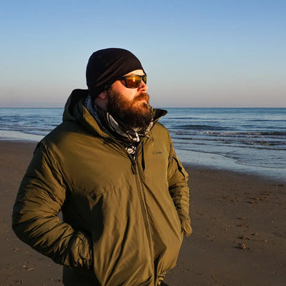 Bearded man in Snugpak Arrowhead Jacket enjoying beach vibes in winter gear