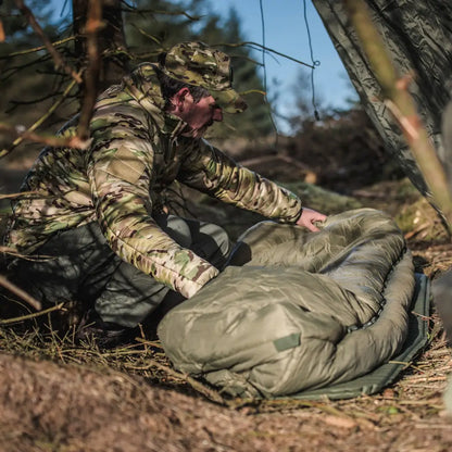 Soldier in camouflage helping someone in a Snugpak sleeping bag under city lights